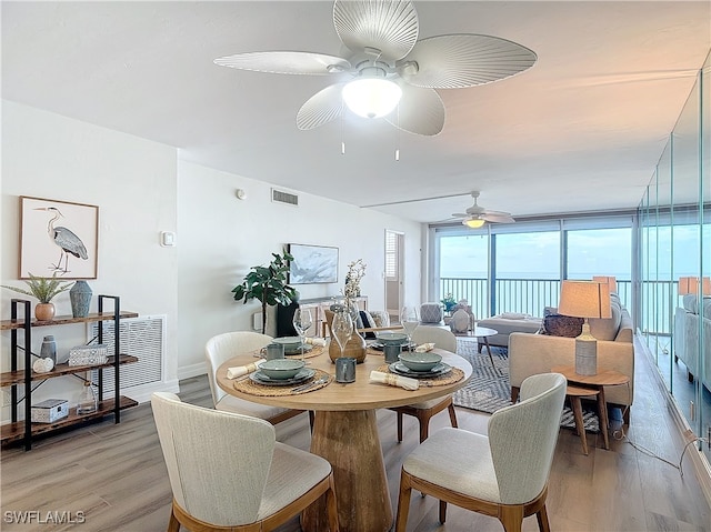 dining space featuring ceiling fan, floor to ceiling windows, and light hardwood / wood-style flooring