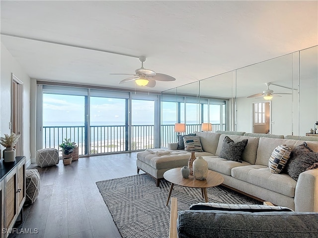 living room featuring a water view, a wealth of natural light, floor to ceiling windows, and hardwood / wood-style flooring