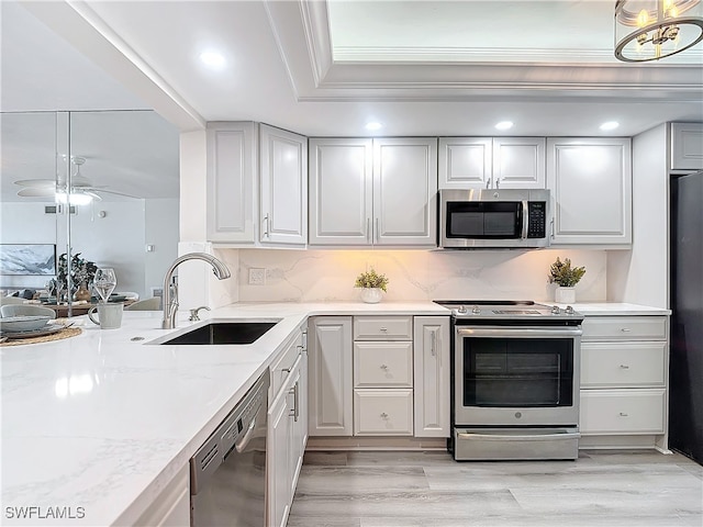 kitchen featuring light stone countertops, sink, light hardwood / wood-style flooring, and black appliances