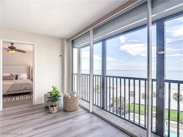 sunroom / solarium with ceiling fan and a water view