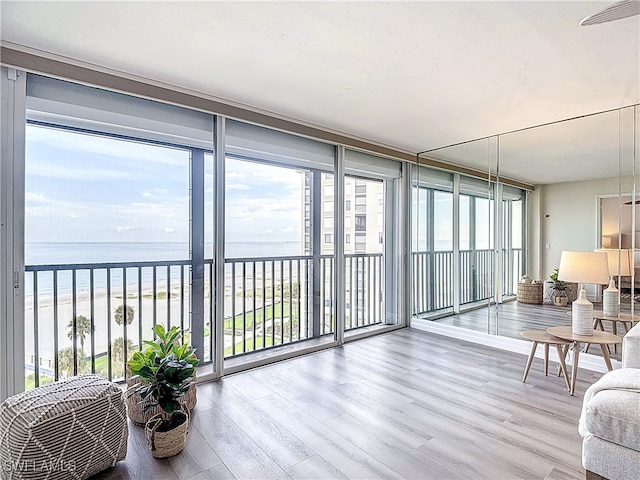 sunroom featuring a water view and a beach view