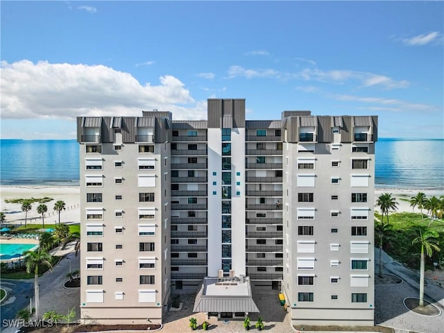 view of building exterior featuring a water view and a beach view