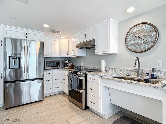 kitchen featuring light stone countertops, appliances with stainless steel finishes, white cabinets, and sink