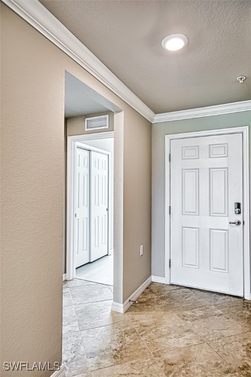 foyer entrance featuring ornamental molding and a textured ceiling