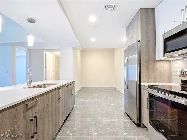 kitchen featuring stainless steel appliances, tasteful backsplash, hanging light fixtures, and sink