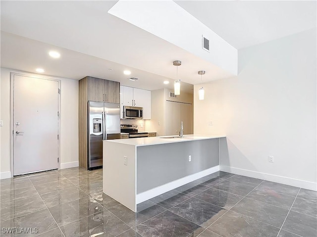 kitchen with stainless steel appliances, decorative light fixtures, kitchen peninsula, and sink