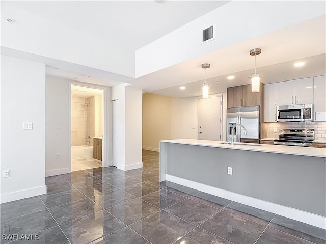 kitchen featuring sink, white cabinetry, stainless steel appliances, tasteful backsplash, and decorative light fixtures