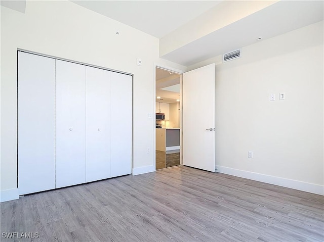 unfurnished bedroom featuring a closet and light wood-type flooring