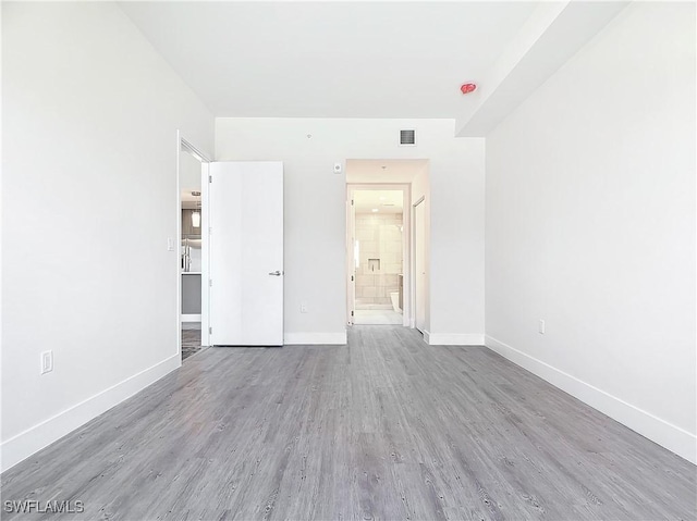 unfurnished bedroom with connected bathroom and hardwood / wood-style floors