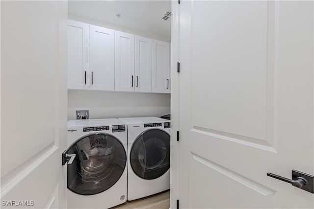 washroom with cabinets, light hardwood / wood-style flooring, and washer and clothes dryer