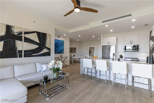 living room with ceiling fan and light hardwood / wood-style floors