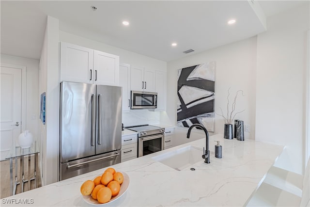 kitchen featuring light stone counters, sink, and stainless steel appliances