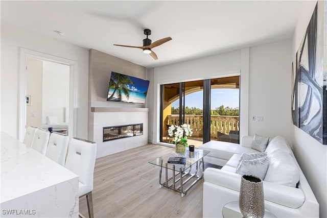 living room with a fireplace, light hardwood / wood-style flooring, and ceiling fan