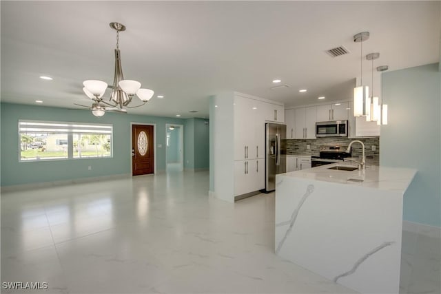 kitchen with light stone countertops, stainless steel appliances, decorative light fixtures, a notable chandelier, and white cabinetry