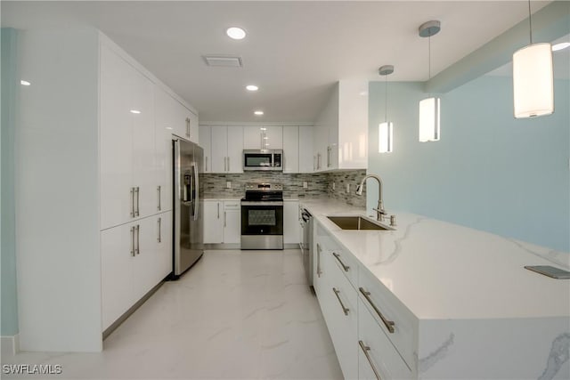 kitchen with backsplash, sink, hanging light fixtures, white cabinetry, and stainless steel appliances