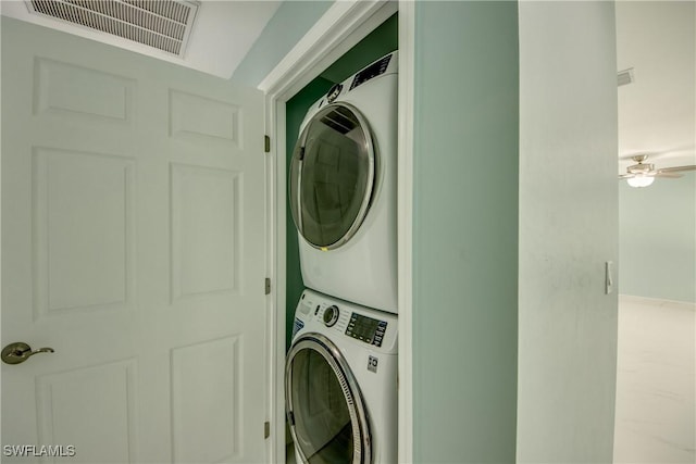 clothes washing area featuring ceiling fan and stacked washing maching and dryer