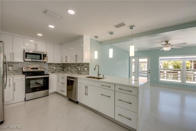 kitchen featuring white cabinets, sink, decorative light fixtures, kitchen peninsula, and stainless steel appliances