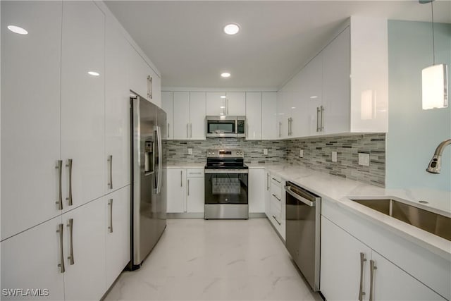 kitchen with tasteful backsplash, stainless steel appliances, sink, white cabinetry, and hanging light fixtures