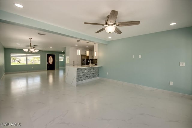 unfurnished living room featuring ceiling fan and sink