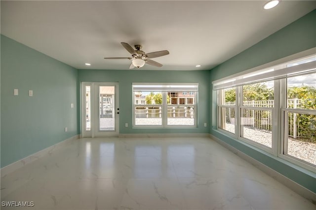 unfurnished sunroom featuring ceiling fan and a healthy amount of sunlight