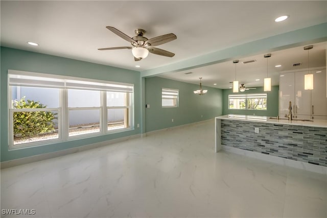 kitchen with white cabinets, ceiling fan with notable chandelier, pendant lighting, and sink