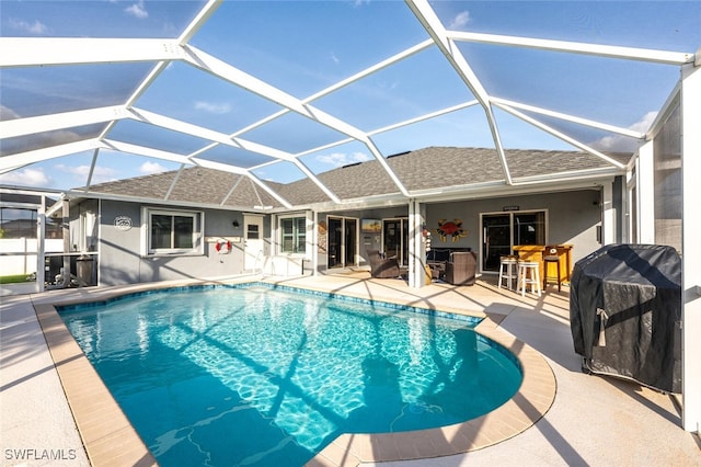 view of swimming pool with an outdoor bar, a patio, glass enclosure, and a grill