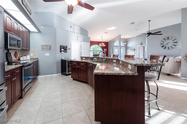 kitchen with a kitchen breakfast bar, vaulted ceiling, appliances with stainless steel finishes, a spacious island, and sink