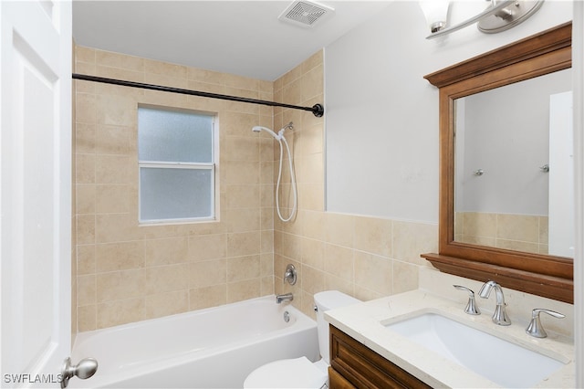 full bathroom with toilet, vanity, tiled shower / bath combo, and tile walls