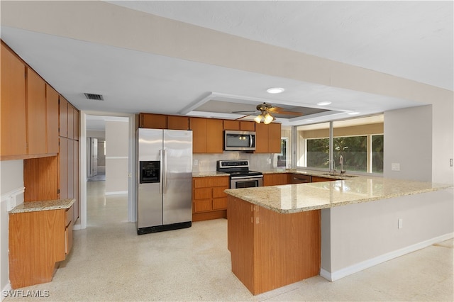 kitchen featuring stainless steel appliances, backsplash, light stone countertops, sink, and kitchen peninsula