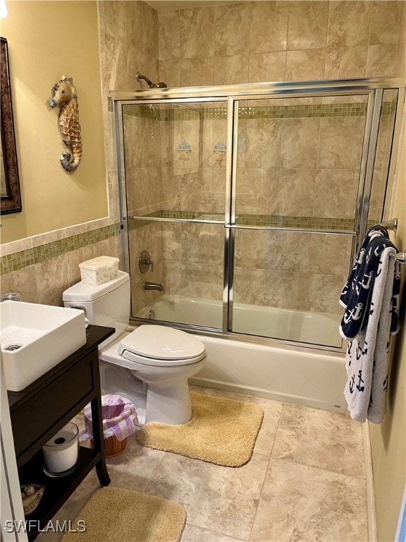 full bathroom featuring vanity, toilet, tile walls, and bath / shower combo with glass door