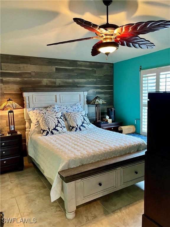 bedroom featuring wooden walls and ceiling fan