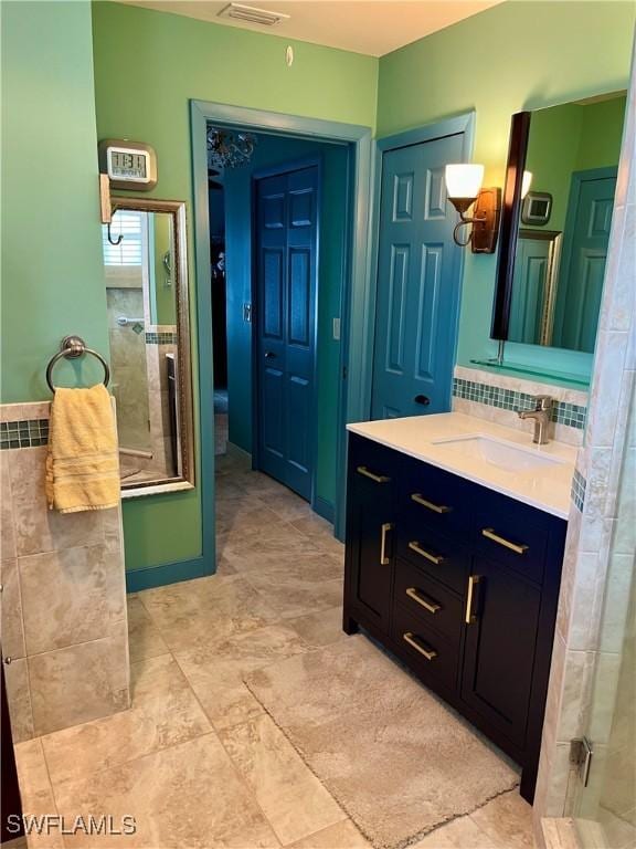 full bath featuring tasteful backsplash, visible vents, vanity, and walk in shower