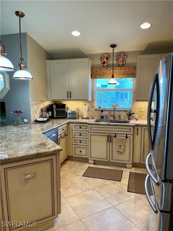 kitchen featuring decorative backsplash, stainless steel fridge, hanging light fixtures, and sink