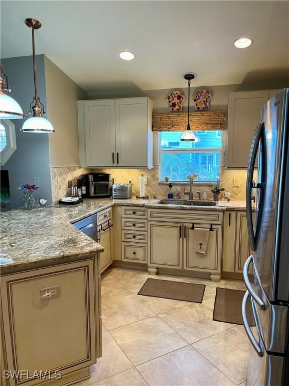 75 Friendship Ln, Englewood, FL 34223 - kitchen featuring freestanding refrigerator, a sink, backsplash, a peninsula, and hanging light fixtures