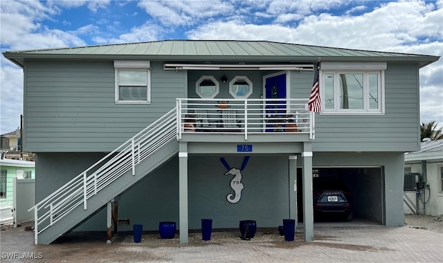 view of front of home featuring metal roof, decorative driveway, stairway, and stucco siding