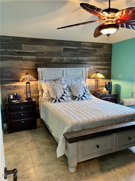 bedroom featuring ceiling fan and wooden walls