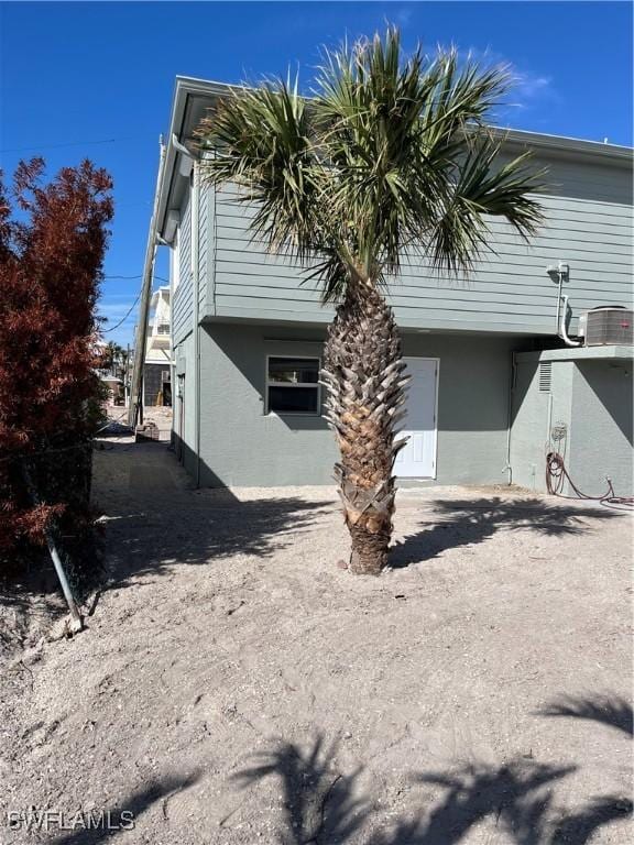 view of side of property with central air condition unit and stucco siding