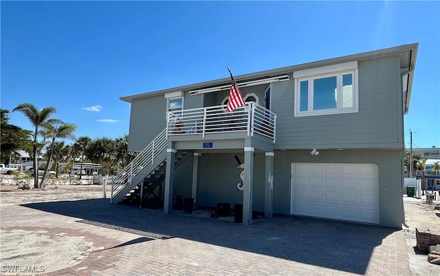 view of front of property with stairs, decorative driveway, an attached garage, and stucco siding