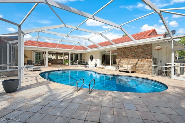 view of swimming pool featuring an outdoor living space, glass enclosure, ceiling fan, and a patio area