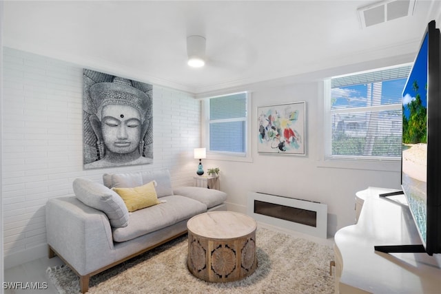 living room with ceiling fan, ornamental molding, and brick wall