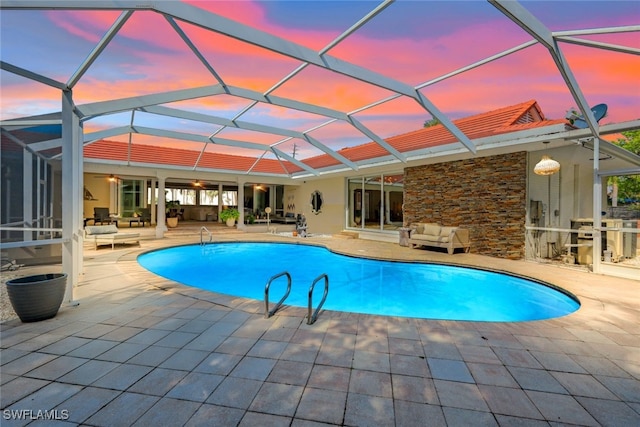 pool at dusk with a patio and glass enclosure