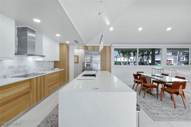 kitchen with white cabinetry, black electric stovetop, a spacious island, and wall chimney range hood