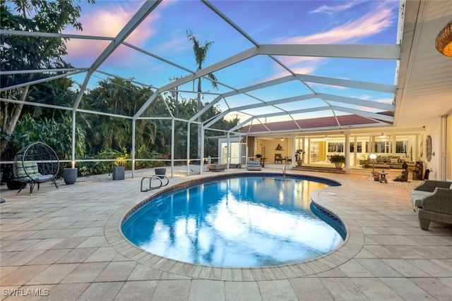 pool at dusk featuring a lanai, an outdoor hangout area, and a patio