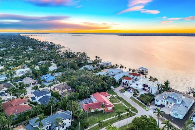 aerial view at dusk featuring a water view