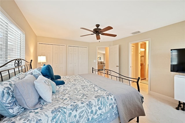 bedroom featuring ceiling fan, two closets, and light tile patterned floors