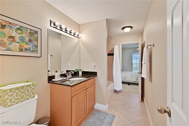 full bathroom featuring toilet, tile patterned floors, a textured ceiling, vanity, and shower / tub combo with curtain