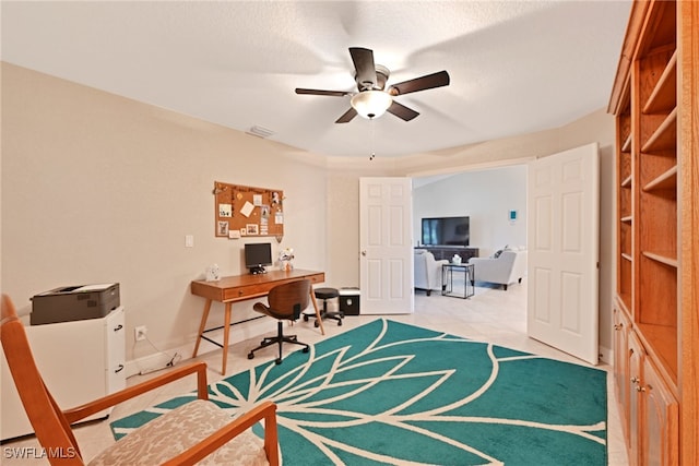 tiled home office with ceiling fan and a textured ceiling