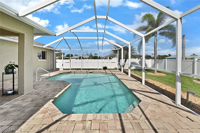 view of pool with glass enclosure, a lawn, and a patio area