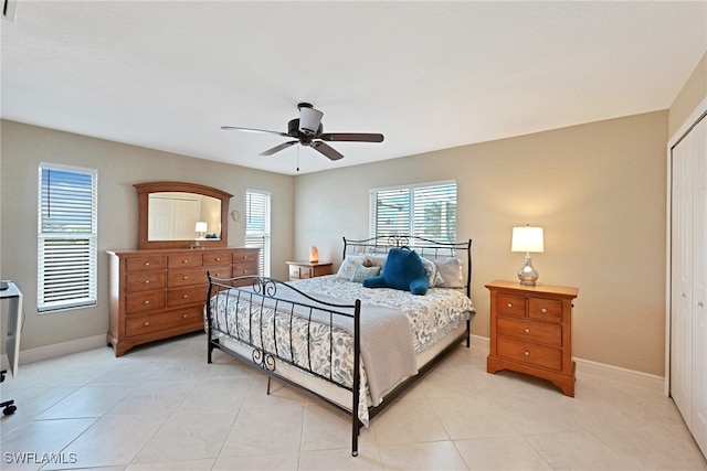 bedroom with a closet, light tile patterned floors, and ceiling fan