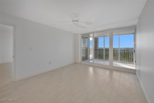 6849 Grenadier Blvd Unit 603, Naples, FL 34108 - empty room featuring expansive windows, light wood-type flooring, a ceiling fan, and baseboards